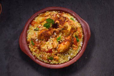 Jeera pilavı ve baharat kullanarak tavuk dhum biryani gri arka planda raitha ve limon turşusu eşliğinde toprak malzemesi..