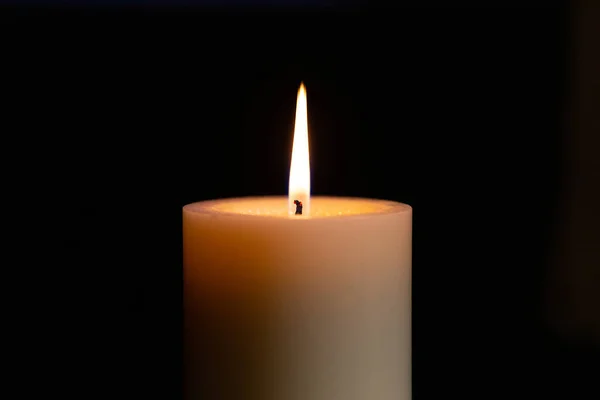 white burning candle on a dark background
