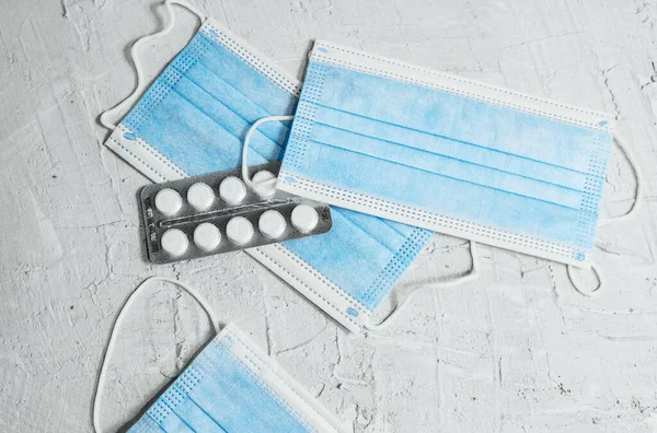 Solunum maskesi, mavi zemin üzerinde el ve tablet antibakteriyel kullanımı.