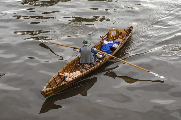 man rowing his boat, on his back, crossing the river with the purchases for his home