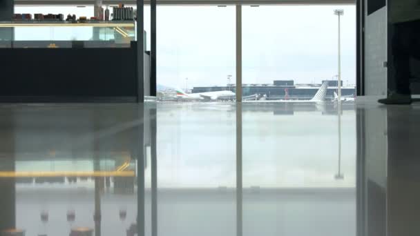 Person mit Koffer am Fenster im Flughafen — Stockvideo