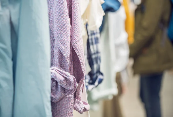 Diferentes camisas de hombre colgando dentro de la tienda de ropa —  Fotos de Stock