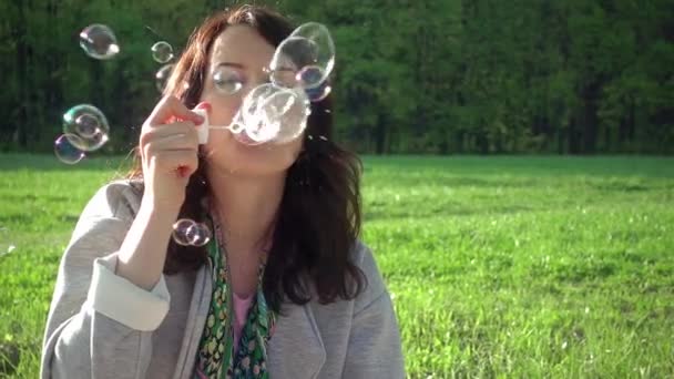 Lindo caucásico chica soplando jabón burbujas en parque — Vídeo de stock