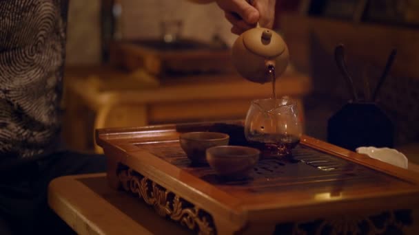 Manos vertiendo la infusión de té en la tetera de vidrio — Vídeos de Stock
