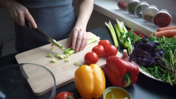 Jovem mulher cortando legumes na cozinha para salada fresca — Vídeo de Stock