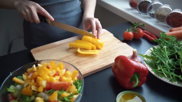 Молодая женщина режет овощи на кухне для свежего салата — стоковое видео