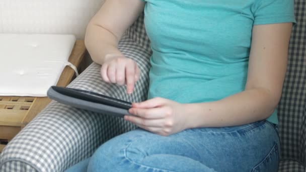 Жінка використовує планшет на кріслі в кімнаті — стокове відео