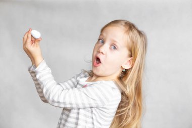 Sarışın bir kız elinde küçük bir çoban yumurtasıyla, Paskalya, çizgili ceketli bir kız, mavi gözlü bir kız.