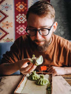 Restoranda yeşil khinkali yiyen sakallı adam..