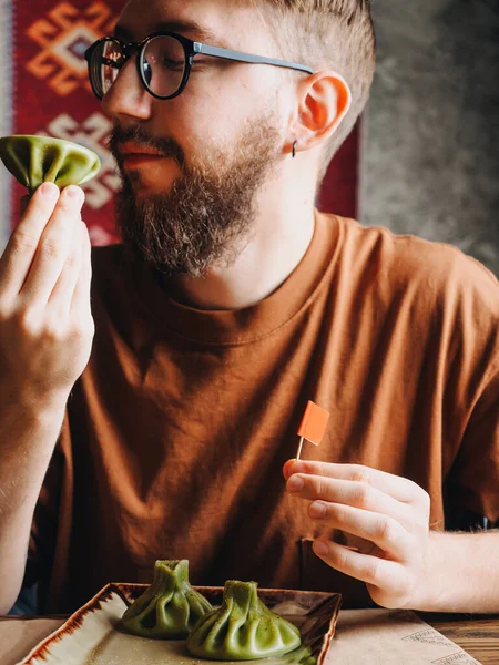 大胡子的家伙在餐馆里吃绿色的金银花 — 图库照片