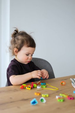 Çocuk boncuk ve iple oynuyor. Güzel motor beceri geliştirme. Erken eğitim, Montessori Yöntemi