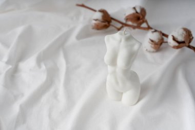 Beyaz kumaş arka planda bir kadın figürü şeklinde mum. Kumaş dokusundaki kadın figürü. Davet için kartpostal.