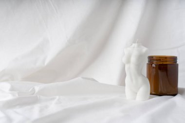 Beyaz kumaş arka planda bir kadın figürü şeklinde mum. Kumaş dokusundaki kadın figürü. Davet için kartpostal.