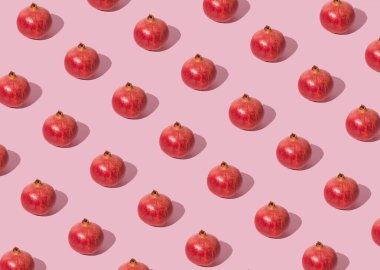 Pastel pembe arka planda nar desenli yaz meyvesi kavramı.