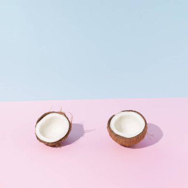 Hindistancevizi pastel pembe ve mavi arka planda ikiye bölünmüş. Tropik meyve yaratıcı konsept. Yaz asgari bileşimi.