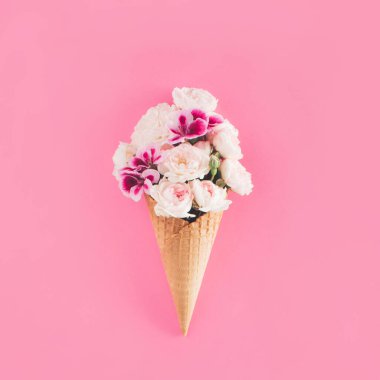 Pembe arka planda gül çiçeğinden yapılmış dondurma külahı. Bahar çiçekleri gibi yaratıcı bir bahçe. Eski moda yaz buketi konsepti.