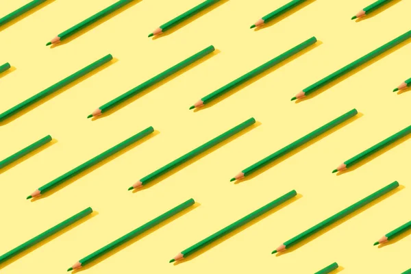 Green pencils pattern on trendy yellow background. Isometric composition. Back to school.