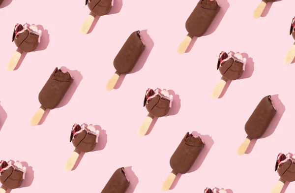 パステルピンクの背景にスティック上のチョコレートアイスクリームパターン クリスピーでおいしい さわやかな甘いデザート 最小限の夏の冷凍食品の概念 最上階だ — ストック写真
