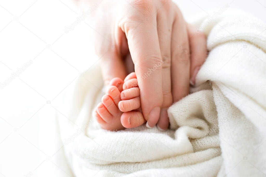 Feet of the newborn in the hands of the mother. Mother holds babys feet in her hands. Happy family concept.
