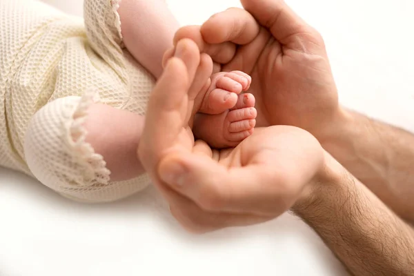 Los pies de los niños en las manos del padre sobre blanco. Padre e hijo recién nacido. Concepto de familia feliz. — Foto de Stock