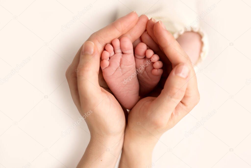 Childrens feet in hold hands of mother on white. Mother and newborn Child. Happy Family people concept.