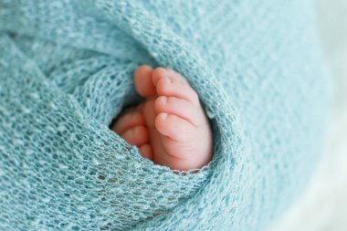Mavi-yeşil bir örgü örülmüş iki şirin bebek ayağı.