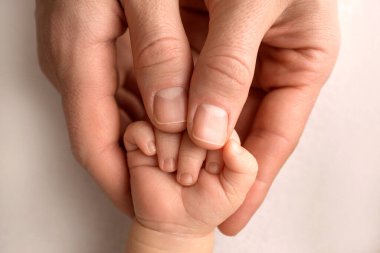 Yeni doğmuş bir bebek annelere, babaların parmaklarına tutunur. Ebeveynlerin elleri ve bebeğin elleri yakın. Bir çocuk ona güveniyor ve sıkıca sarılıyor.