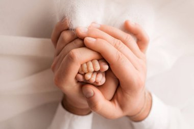 Anne ve babanın ellerinde çocuk ayakları var. Anne, baba ve çocuk. Mutlu Aile kavramı.