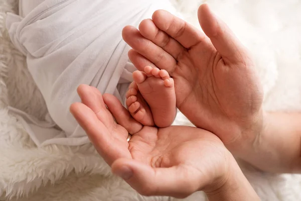 Los pies de los niños en las manos de la madre y el padre. Madre, padre e hijo. Concepto de familia feliz. — Foto de Stock