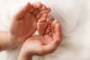 Anne ve babanın ellerinde çocuk ayakları var. Anne, baba ve çocuk. Mutlu Aile kavramı.