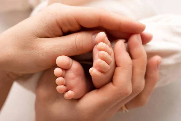 Pequeños pies de un niño recién nacido en manos de un padre. Un bebé de una semana. La imagen de los primeros días de vida. Imagen conceptual de familia feliz, maternidad e infancia feliz. — Foto de Stock