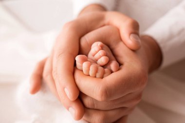 Yeni doğmuş bir çocuğun küçük ayakları bir ebeveynin ellerinde. Bir haftalık bebek. Hayatın ilk günlerinin görüntüsü. Mutlu aile imajı, annelik ve mutlu çocukluk..