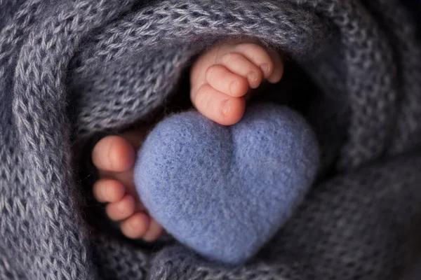 Dos lindos pequeños pies de bebé envueltos en una manta de punto azul-verde aqua. Y un corazón de punto hecho de hilos de lana. —  Fotos de Stock