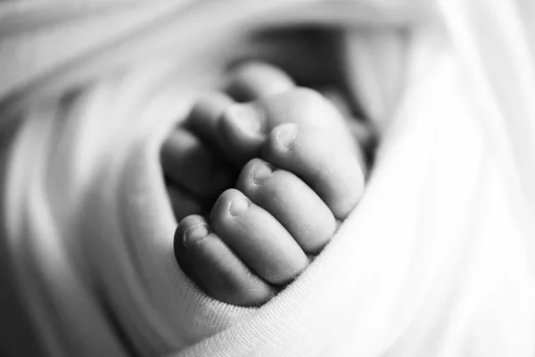 Kleine voetjes. De kleine voet van een pasgeborene in zachte selectieve focus. Zwart-wit beeld van de voetzolen. — Stockfoto