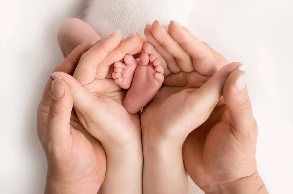 Hands of parents. the legs of the newborn in the hands of mom and dad. babys legs in his hands. — Stock Photo, Image