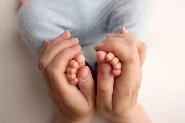 Föräldrars händer. Benen på det nyfödda barnet i händerna på mamma och pappa. Babys ben i sina händer. — Stockfoto