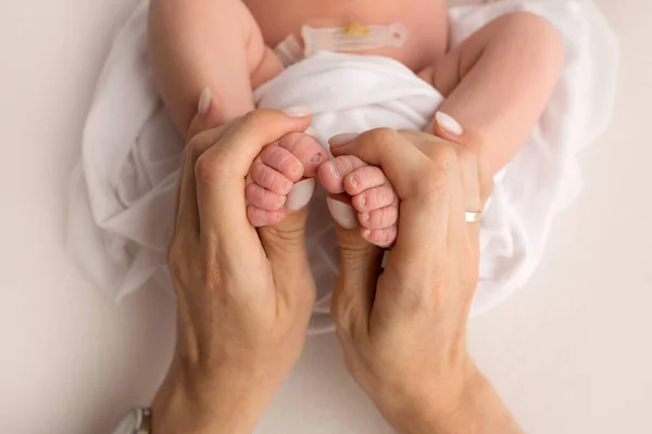 Mains des parents. les jambes du nouveau-né dans les mains de maman et papa. jambes de bébé dans ses mains. — Photo