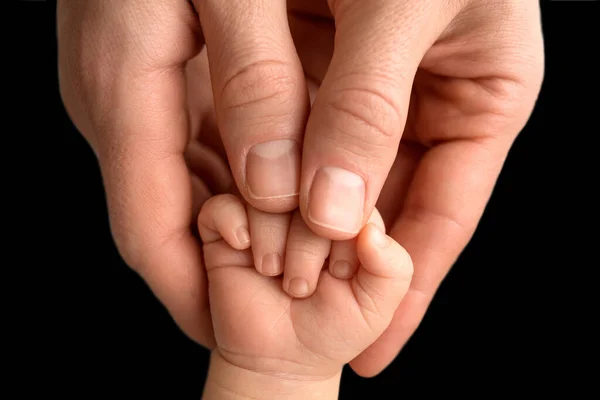 Pai segurando recém-nascidos bebês fingersnewborn. Mão de um recém-nascido. Mãos de pais e fechadura do bebê. Preto estúdio fundo. — Fotografia de Stock