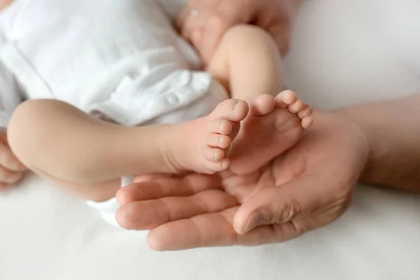 Föräldrars händer. Benen på det nyfödda barnet i händerna på mamma och pappa. Babys ben i sina händer. — Stockfoto