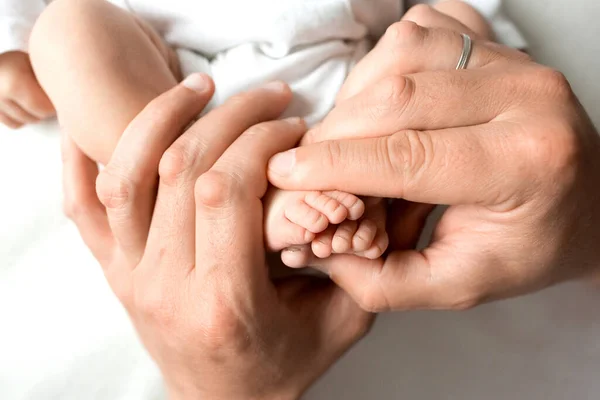 Manos de los padres. las piernas del recién nacido en manos de mamá y papá. babys piernas en sus manos. — Foto de Stock