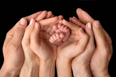 Anne, baba ve çocuğun elleri yeni doğmuş bebek ayaklarını tutuyor. Bebekli şirin bir aile fotoğrafı..