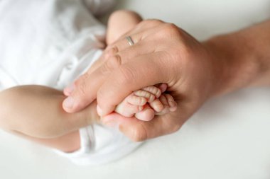 Ebeveynlerin elleri. Yeni doğan bebeğin bacakları anne ve babanın ellerinde. Ellerindeki bebek bacakları. 