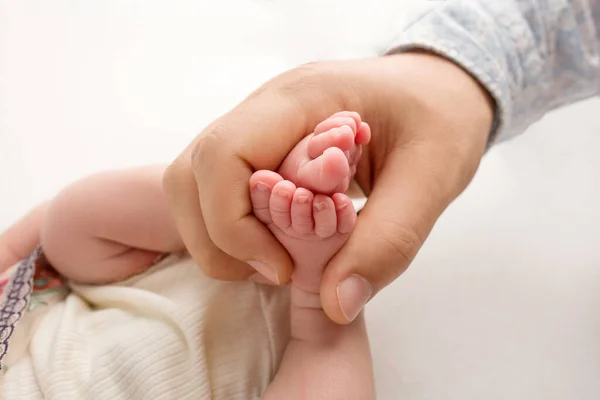 Les mains des parents. Les jambes, les pieds du nouveau-né dans les mains de maman et papa. — Photo