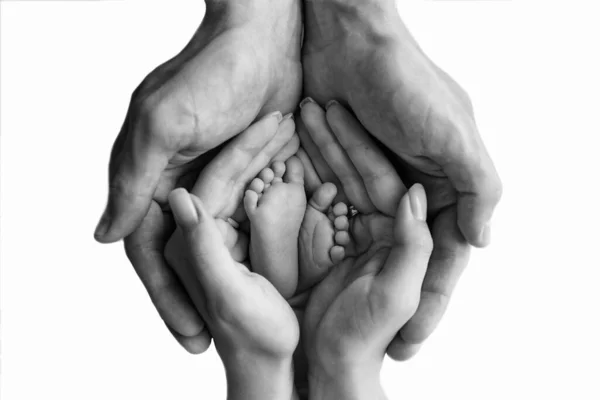 Ebeveynler yeni doğmuş ayakları tutuyor, yakın plan. Siyah beyaz fotoğraf. — Stok fotoğraf