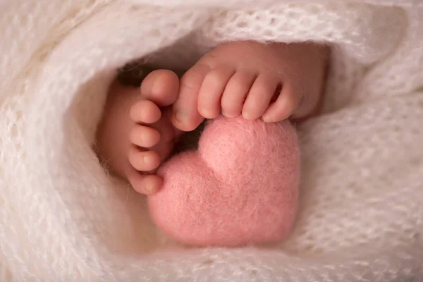 Piernas y dedos de los pies de un recién nacido en una manta blanca suave con un corazón rosado —  Fotos de Stock