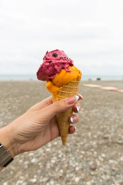 Ice cream in a waffle cup in the hand of a girl on the beach of Batumi — Stock Photo, Image