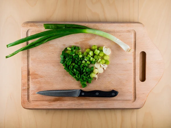 Forma de corazón formada por un manojo de cebolla con cuchillo — Foto de Stock