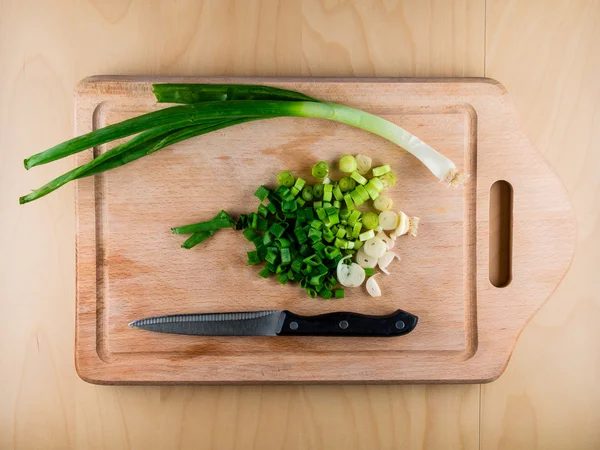 Cebolla en rodajas en tabla de madera con cuchillo —  Fotos de Stock