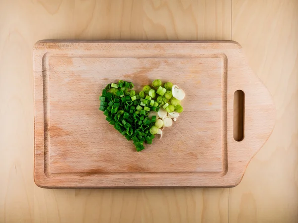 Heart shape formed from bunch onion on board — Stock Photo, Image