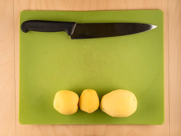 三个土豆和绿色的塑料板刀 — 图库照片